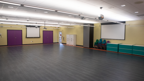 Community Room with open floor, projection screens, and cabinets along the walls.